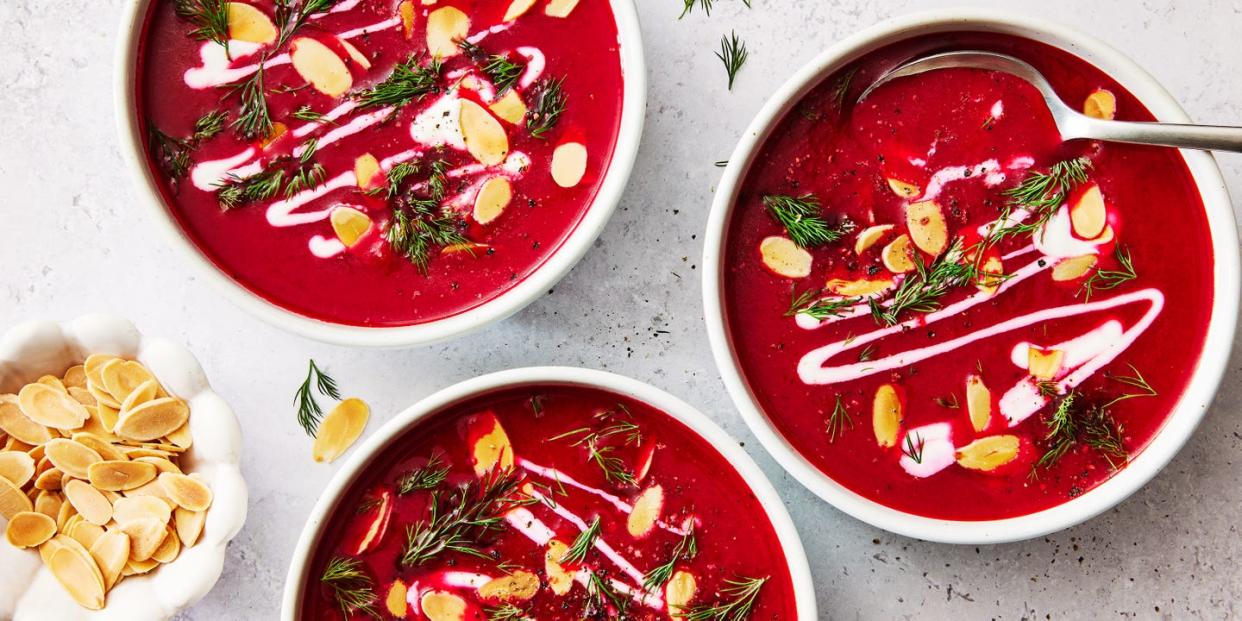 one pot harissa beet soup in a white bowl topped with almonds, herbs, and cream