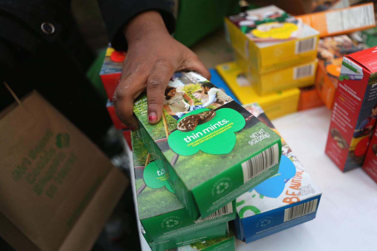 Woman’s Hand on Boxes of Girl Scout Cookies Thin Mints, Other Boxes in the Background