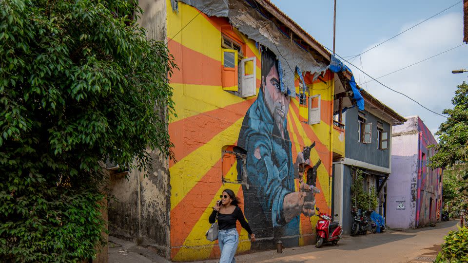 A woman walks past a mural portraying Bollywood Indian actor Dharmendra in Mumbai, India, on April 17, 2024. - Noemi Cassanelli/CNN