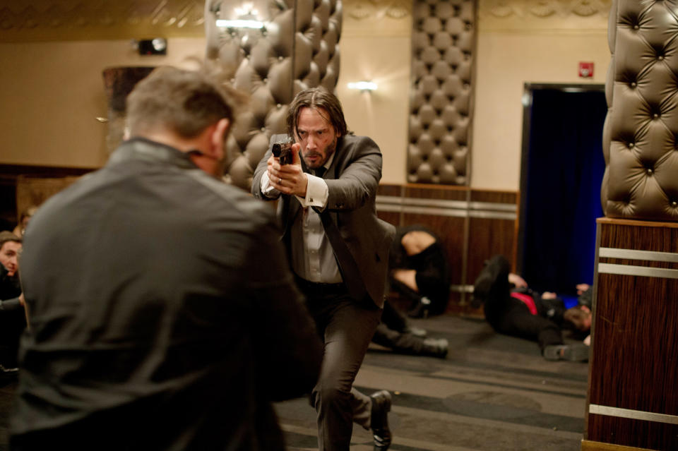 Keanu Reeves pointing a gun while running