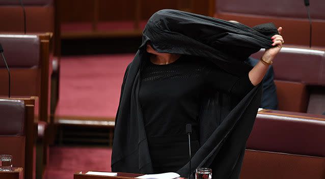 Senator Hanson starts to rip off the burqa before she begins to speak. Photo: AAP