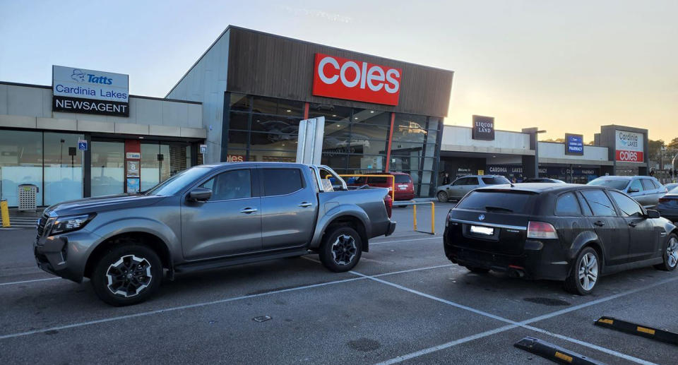 Grey ute parking in Coles shopping centre car park across two spaces