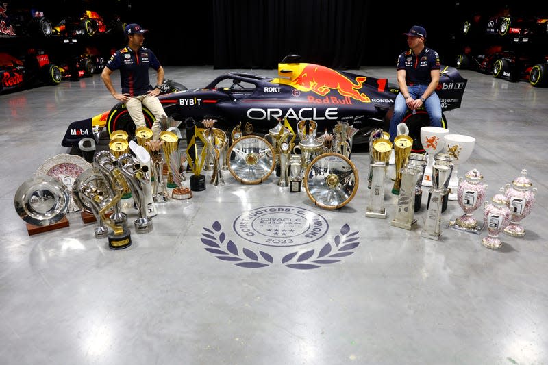 Sergio Perez of Mexico and Oracle Red Bull Racing (L) and Max Verstappen of the Netherlands and Oracle Red Bull Racing pose for a photo with trophies during Max & Checo's Homecoming at Red Bull Racing Factory on December 13, 2023 in Milton Keynes, England