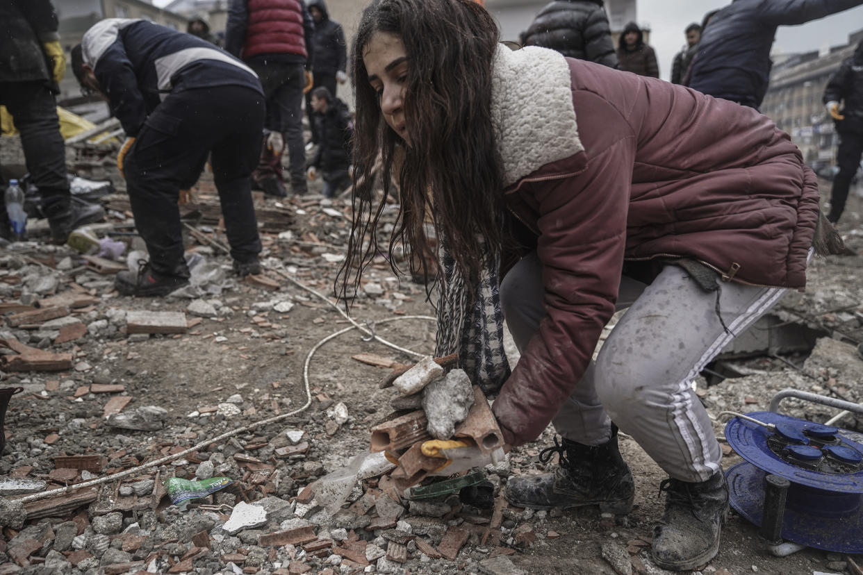 A young women removes debris from a destroyed building as she searches for people with emergency teams in Gaziantep, Turkey, Monday, Feb. 6, 2023. (AP Photo/Mustafa Karali)