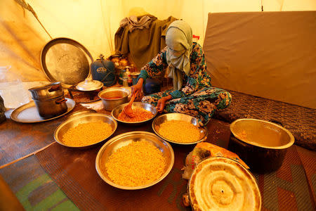 A Libyan woman displaced from the town of Tawergha prepares food at a camp in the Garart al-Gatef, Libya March 25, 2018. REUTERS/Ismail Zitouny