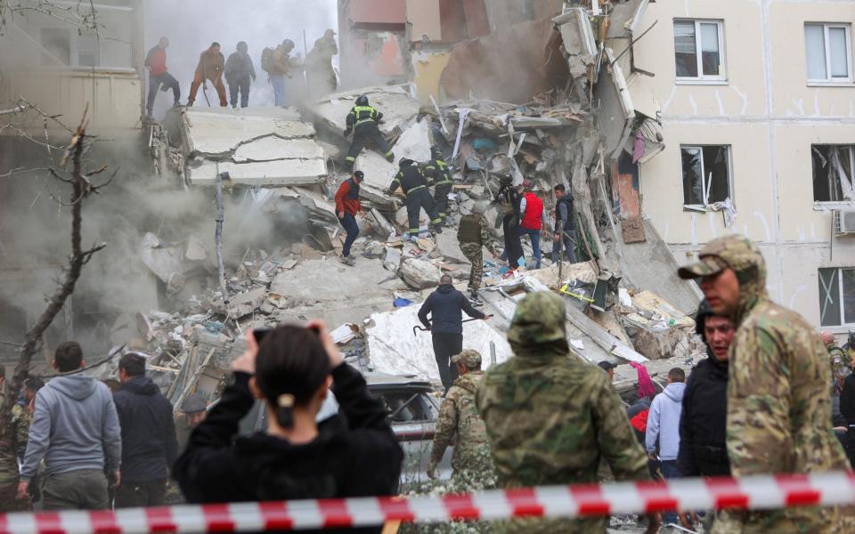 People remove debris while searching for survivors following the collapse of a section of a multi-story apartment block, as the result of what local authorities called a Ukrainian missile strike, in the course of Russia-Ukraine conflict in the city of Belgorod, Russia, May 12, 2024.