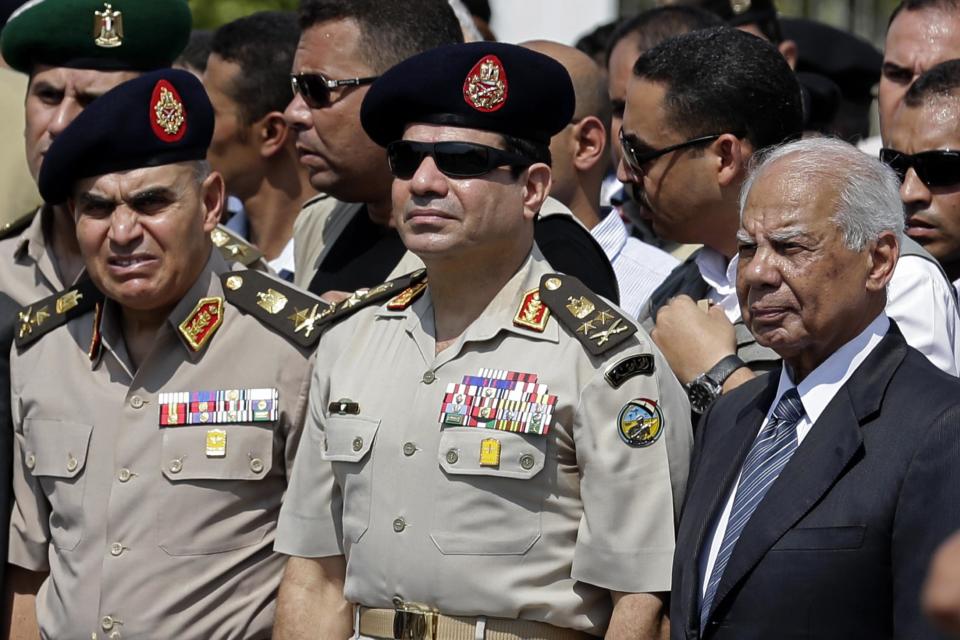 FILE - In this Friday, Sept. 20, 2013 file photo, Egypt's Defense Minister Gen. Abdel-Fattah el-Sissi, center, Egyptian Prime Minister Hazem el-Beblawi, right, and army's Chief of Staff Lt. Gen. Sedki Sobhi, left, attend the funeral of Giza Police Gen. Nabil Farrag in Cairo, Egypt. Egypt’s interim prime minister Hazem el-Beblawi announced Monday the resignation of his Cabinet, a surprise move that could be designed in part to pave the way for the nation’s military chief to leave his defense minister’s post to run for president. El-Beblawi has often been derided in the media for his perceived indecisiveness and inability to introduce effective remedies to the country’s economic woes. (AP Photo/Hassan Ammar, File)