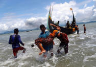 Smoke is seen on Myanmar's side of border as an exhausted Rohingya refugee woman is carried to the shore after crossing the Bangladesh-Myanmar border by boat through the Bay of Bengal, in Shah Porir Dwip, Bangladesh September 11, 2017. REUTERS/Danish Siddiqui