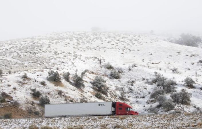 Rebec, CA-December 14, Tuesday, December 14, 2021, traffic flows past the snow-covered hills of Rebec, California, through Interstate 5. A cold storm brought rain and snow to southern California.  (Myeong J. Chun / Los Angeles Times)