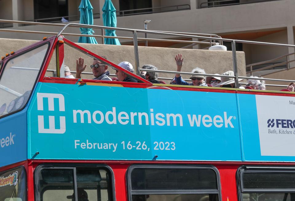 People wave from atop the double decker bus during an architectural tour as part of Modernism Week in Palm Springs, Calif., Feb. 16, 2023. 