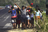 Youths and their families stand on the side of a road asking for help two days after the passage of Hurricane Otis as a Category 5 storm in Los Coyotes near Acapulco, Mexico Friday, Oct. 27, 2023. (AP Photo/Marco Ugarte)