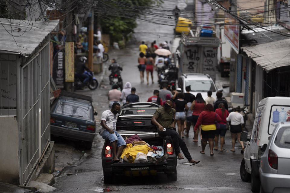 Residents, some wearing masks as a precaution against the spread of the new coronavirus, walk together as they accompany a vehicle transporting the remains of several people who died in an armed confrontation in the Alemao slums complex in Rio de Janeiro, Brazil, Friday, May 15, 2020. According to the civil police, 10 people were found dead during the police operation against alleged drug traffickers. (AP Photo/Leo Correa)