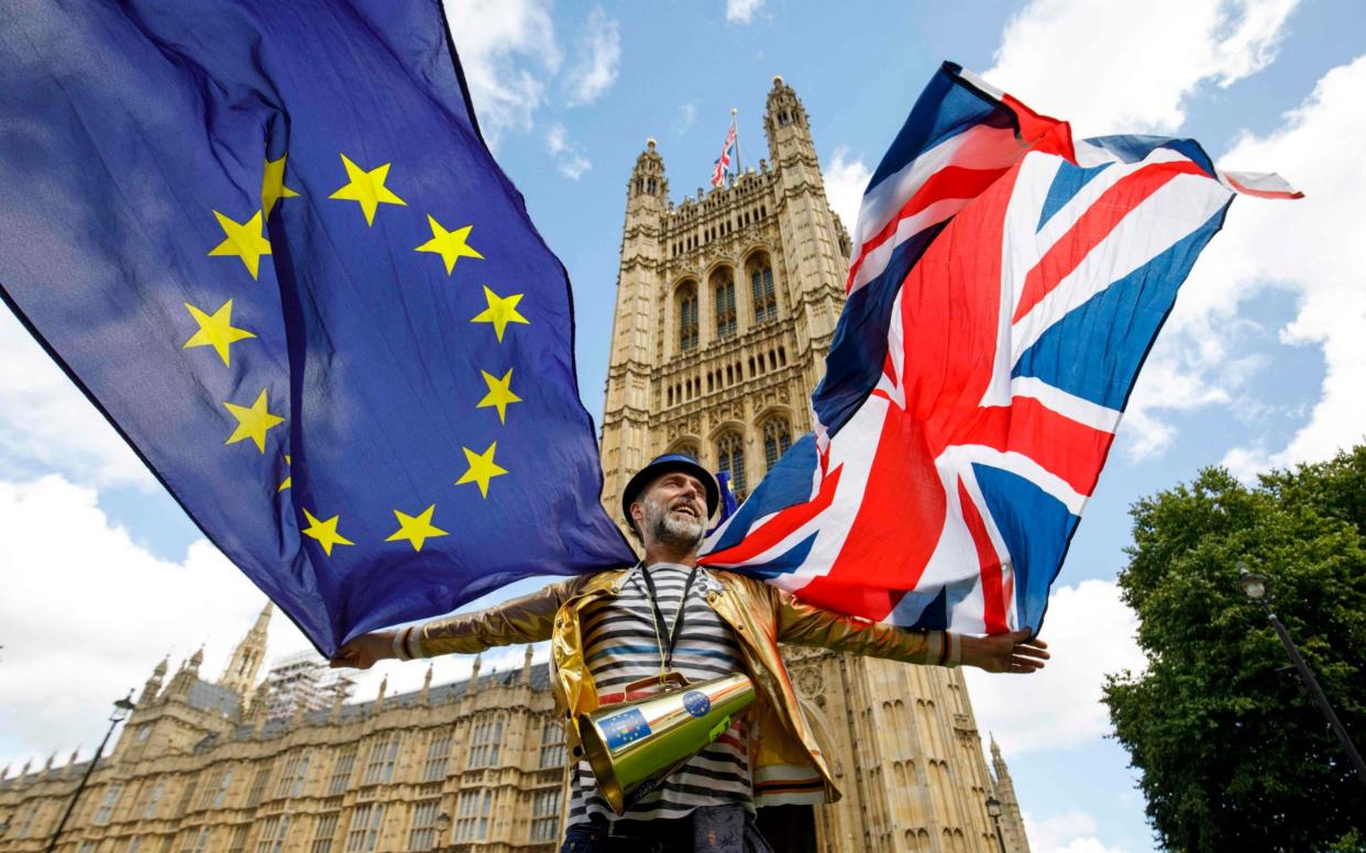 A demonstrator flies the Union flag and the European flag outside the Houses of Parliament - AFP