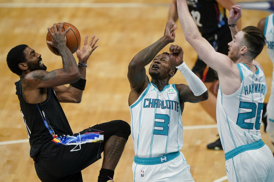 Brooklyn Nets guard Kyrie Irving shoots over Charlotte Hornets forward Gordon Hayward, right, and guard Terry Rozier during the first half of an NBA basketball game in Charlotte, N.C., Sunday, Dec. 27, 2020. (AP Photo/Chris Carlson)