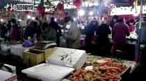 People wearing masks shop at a market in Wuhan