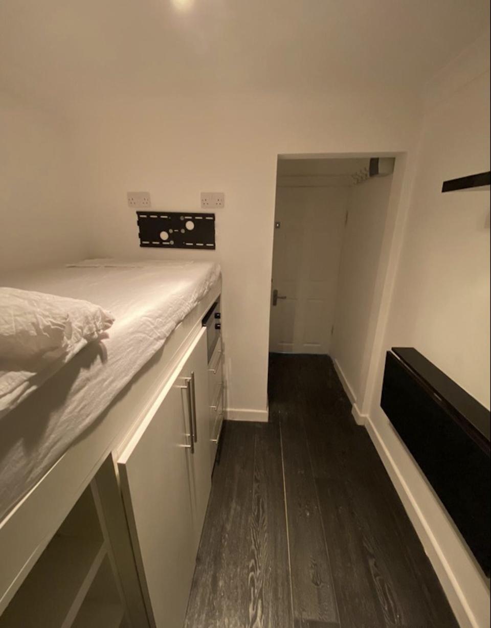 The tiny apartment has a single bed with storage underneath it.