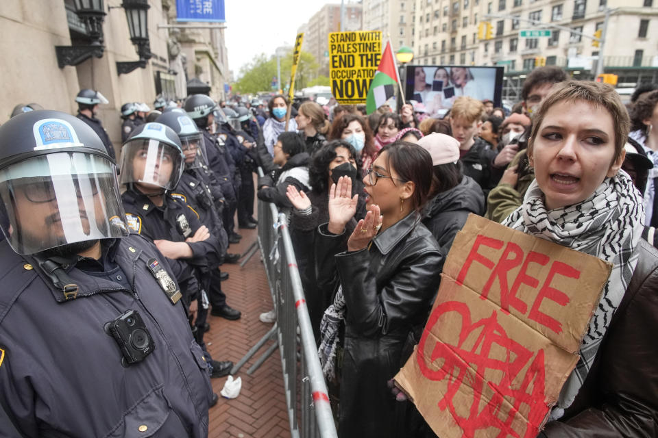 Police in Riot gear stand guard as demonstrators chant slogans outside the Columbia University campus, Thursday, April 18, 2024, in New York. The protesters were calling for the school to divest from corporations they claim profit from the war in the Middle East. (AP Photo/Mary Altaffer)