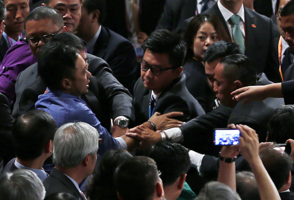 A protester, center left, is ushered away by security officials after he shouted "(for China) To reverse its condemnation of the brutal June 4, 1989 crackdown on protesters in Tiananmen Square and to end to one-party rule in China " before Chinese President Hu Jintao's address after Hong Kong's new Chief Executive Leung Chun-ying was sworn in at the Hong Kong Convention and Exhibition Center Sunday, July 1, 2012. Hong Kong's new Beijing-backed leader was sworn in on Sunday amid a rising tide of public discontent over widening inequality and lack of full democracy in the semiautonomous southern Chinese financial center. (AP Photo/Vincent Yu)