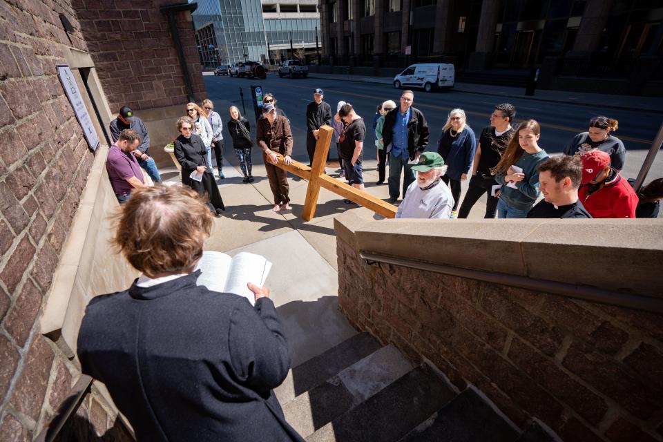 Worshipers read scripture outside the Cathedral Church of St. Paul during the annual downtown Way of the Cross program, Friday, April 7, 2023. 