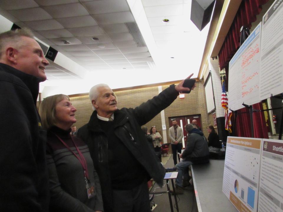 Munroe Falls Fire Chief Lee Chafin, Betty Bradshaw, the administrative assistant to the school district's director of operations, and Munroe Falls Mayor Allen Mavrides look over the boards which allowed residents to vote on various plans for the district.