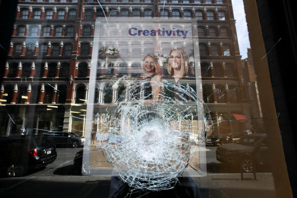 A glass store window is smashed, Wednesday, June 3, 2020, in New York. People broke into stores Tuesday night following peaceful protests over the death of George Floyd, a black man who was killed while in police custody in Minneapolis on May 25. (AP Photo/Mark Lennihan)