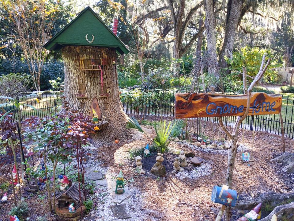 A tree stump designed as a fair and gnome home with a sign that says gnome home.