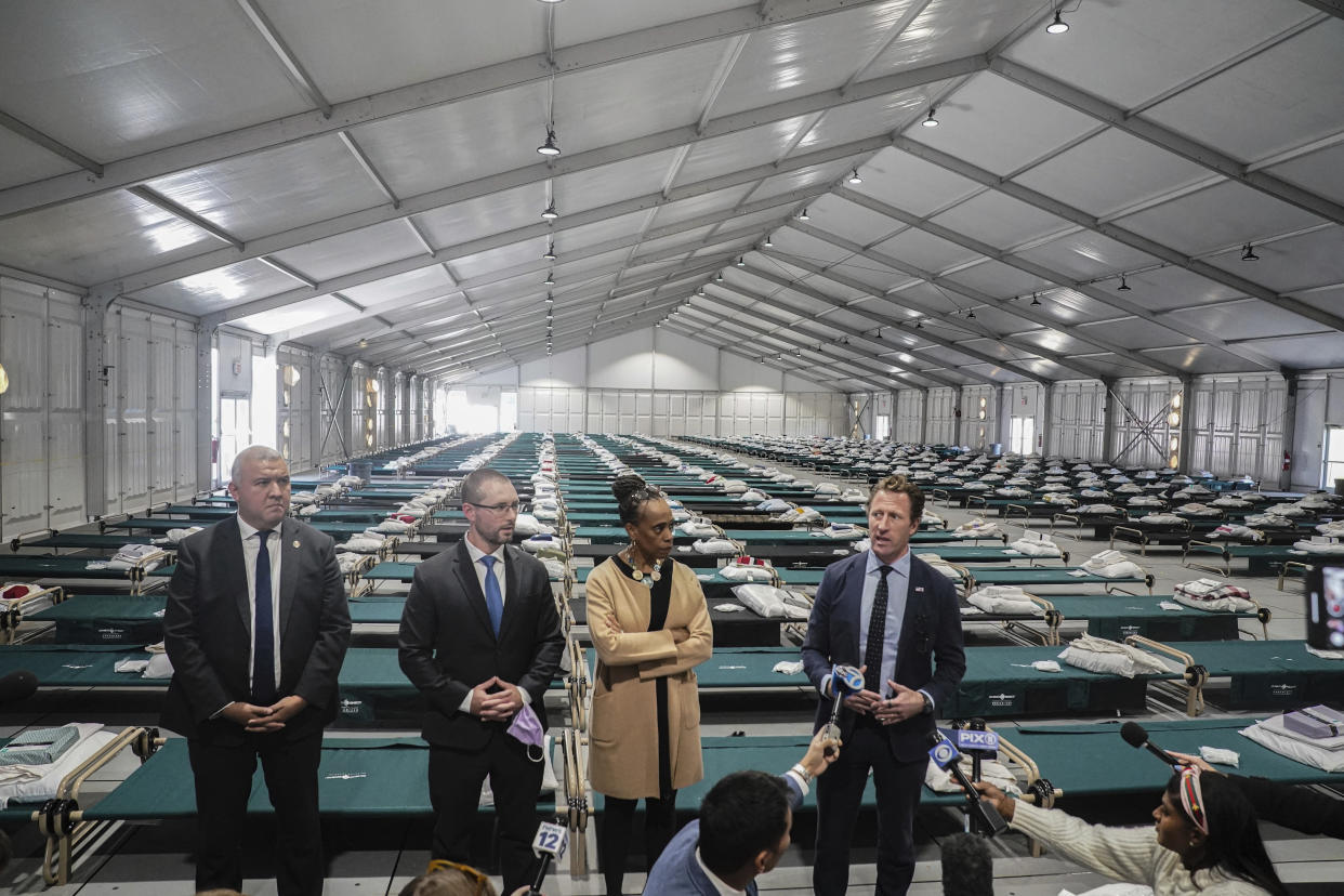 New York's Office of Immigrant Affairs Commissioner Manuel Castro, far left, Health and Hospital Vice President Dr. Ted Long, second from left, Deputy Mayor for Health and Human Services Anne Williams-Isom, second from right, and Emergency Management Commissioner Zach Iscol, far right, hold a news briefing in the sleeping area of the city's latest temporary shelter on Randall's Island, Oct. 18, 2022, in New York. (AP Photo/Bebeto Matthews)