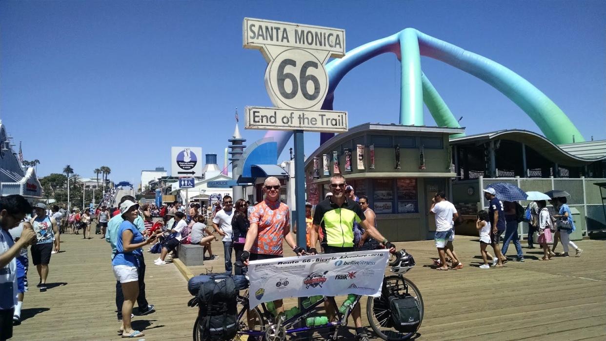 Tracy and Peter Flucke pose under a Route 66 sign at the Santa Monica Pier in California, the end of their 49-day tandem bike odyssey on the historic highway.