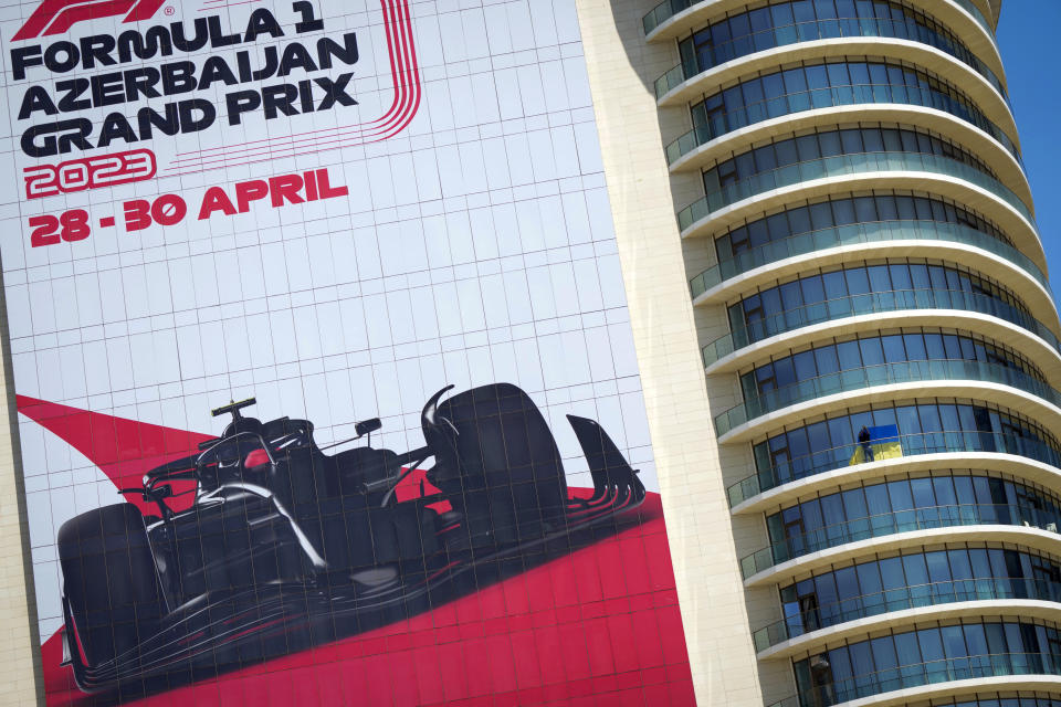 A man fixes a Ukrainian flag on a balcony near the Baku circuit, in Baku, Azerbaijan, Thursday, April 27, 2022. The Formula One Grand Prix will be held on Sunday April 30, 2023. (AP Photo/Sergei Grits)