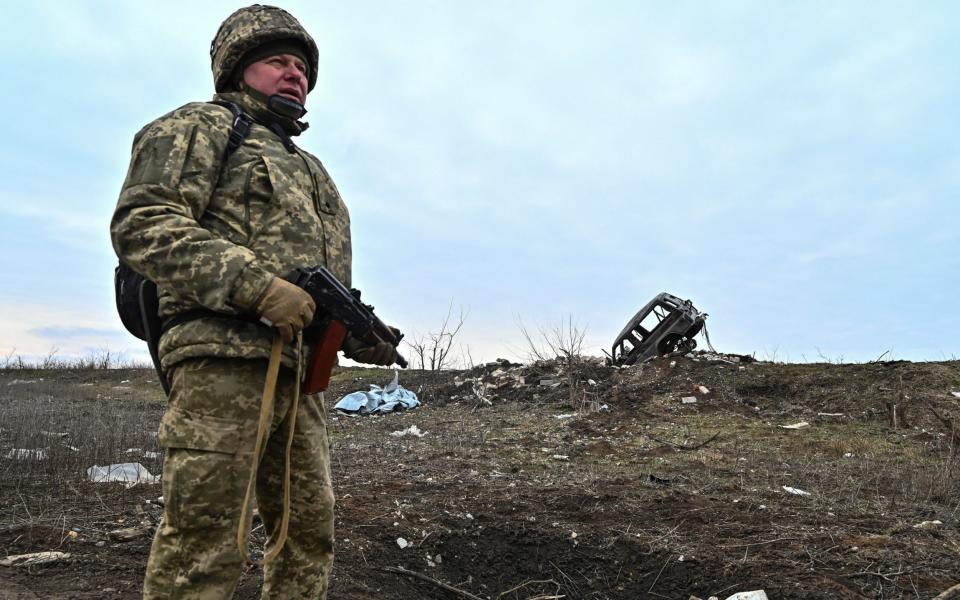 A Ukrainian serviceman of the 65th Mechanised Brigade near a damaged car at the frontline village of Robotyne, in Zaporizhzhia region, on Wednesday