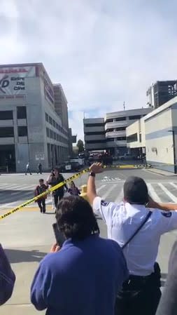 A police officer holds up police tape for pedestrians near the scene of a shooting at the Tanforan Mall shopping center in San Bruno, San Francisco