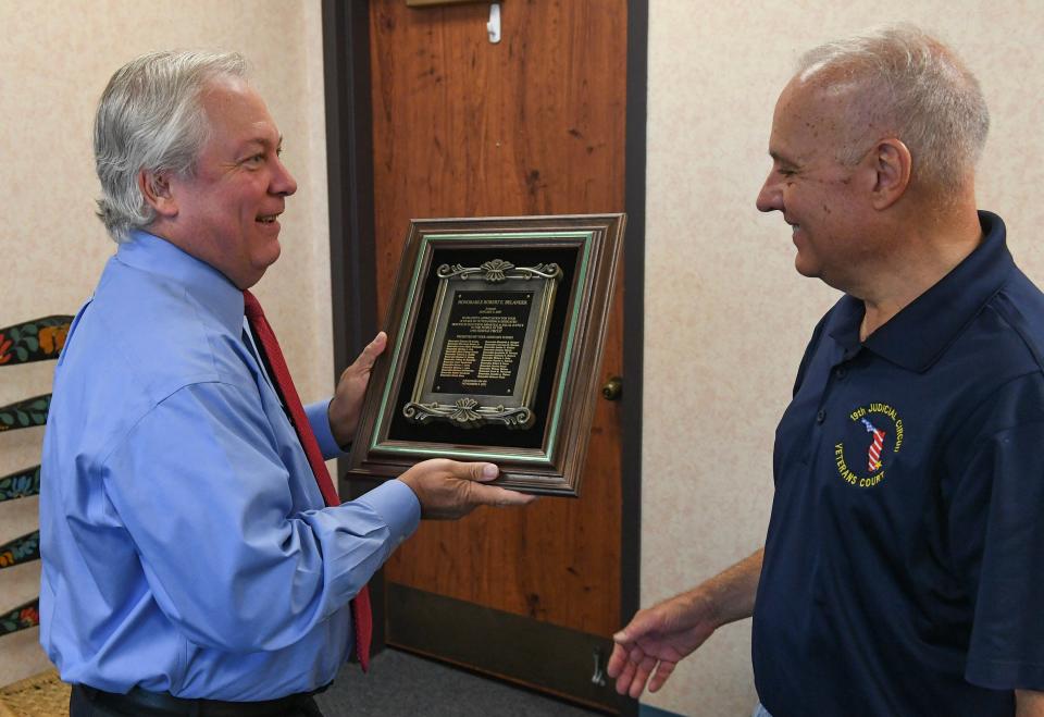 Chief Judge Charles Schwab (left), of the 19th Judicial Circuit Court, presents a commemorative plaque to retiring Circuit Judge Robert Belanger inside Belanger’s chambers in the St. Lucie County Courthouse on Monday, Nov. 6, 2023, in downtown Fort Pierce. Judge Belanger is retiring after 18 years on the bench and 10 years as a high profile state prosecutor in Stuart.