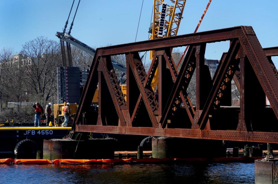 Workers take down the “bridge to nowhere” on the Seekonk River on Thursday.