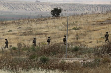 Turkish soldiers walk at the Atmeh crossing on the Syrian-Turkish border, as seen from the Syrian side, in Idlib governorate