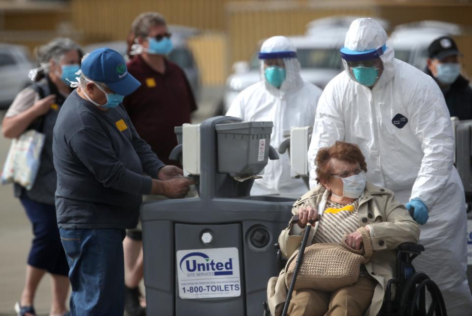 A medical worker assists a passenger from the Princess Cruises Grand Princess cruise ship before boarding a charter plane at Oakland International Airport on March 10, 2020 in Oakland, Calif. Passengers are slowly disembarking from the Princess Cruises Grand Princess a day after it docked at the Port of Oakland.