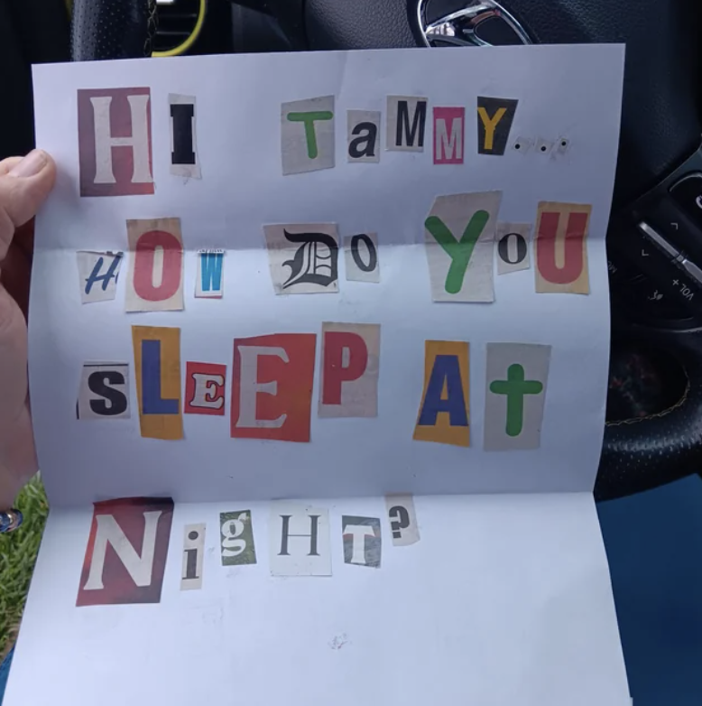 Paper with cutout letters glued on, spelling "Hi Tammy... How do you sleep at night?" held inside a car
