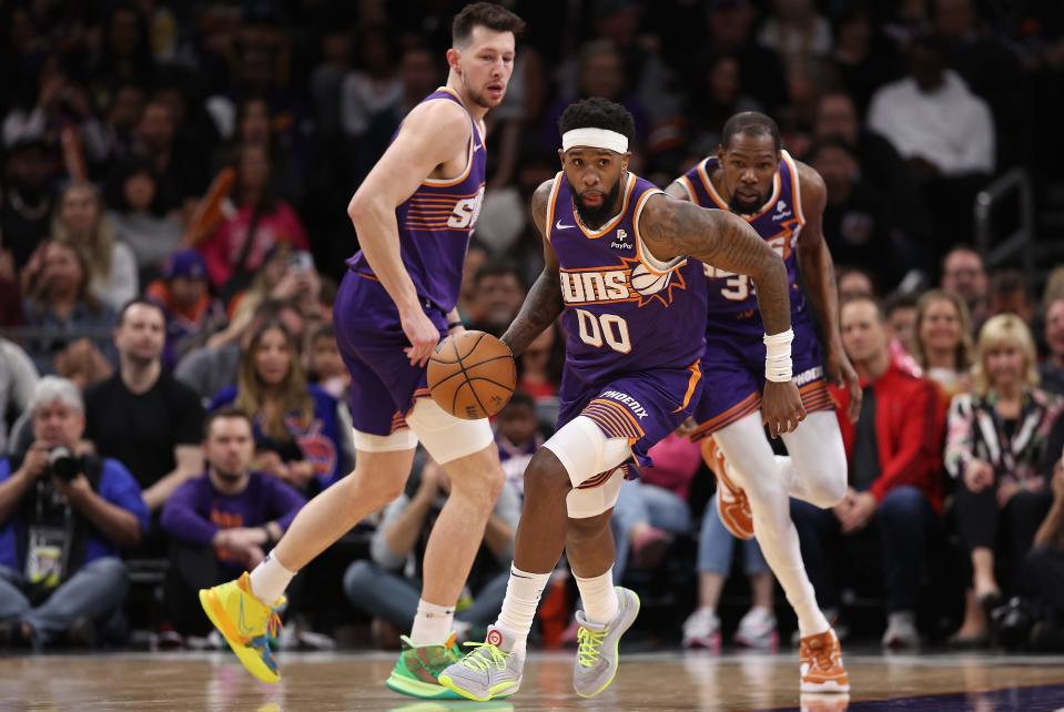 Royce O'Neale #00 of the Phoenix Suns handles the ball ahead of Jusuf Nurkic #20 and Kevin Durant #35 during the second half of the NBA game against the Detroit Pistons at Footprint Center on Feb. 14, 2024 in Phoenix.