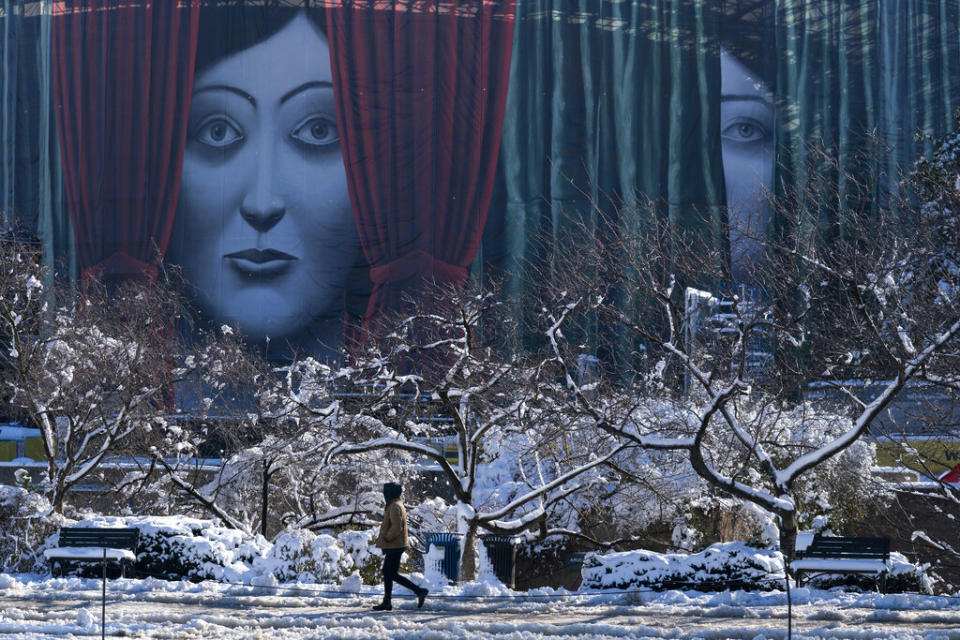 Against the backdrop of scaffolding disguised with a temporary mural, people walk on the National Mall a day after a snow storm passed through the Washington, D.C., region Tuesday. (AP Photo/Evan Vucci)