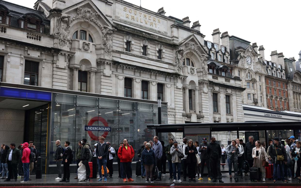 Commuters wait at a bus stop outside Victoria train station in London on June 6, 2022, during a 24-hour strike by nearly 4,000 London Underground station staff. (Photo by Hollie Adams / AFP) (Photo by HOLLIE ADAMS/AFP via Getty Images)
