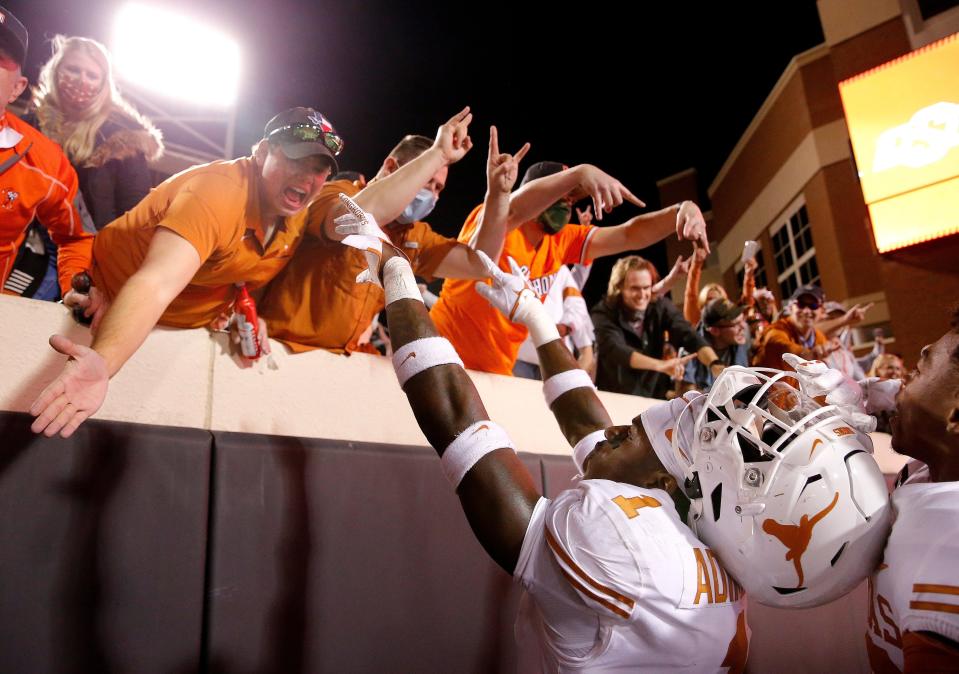 Texas' Chris Adimora celebrates with fans as an Oklahoma State fan does the horns down during a game against Oklahoma State in Stillwater, Okla., Saturday, Oct. 31, 2020.