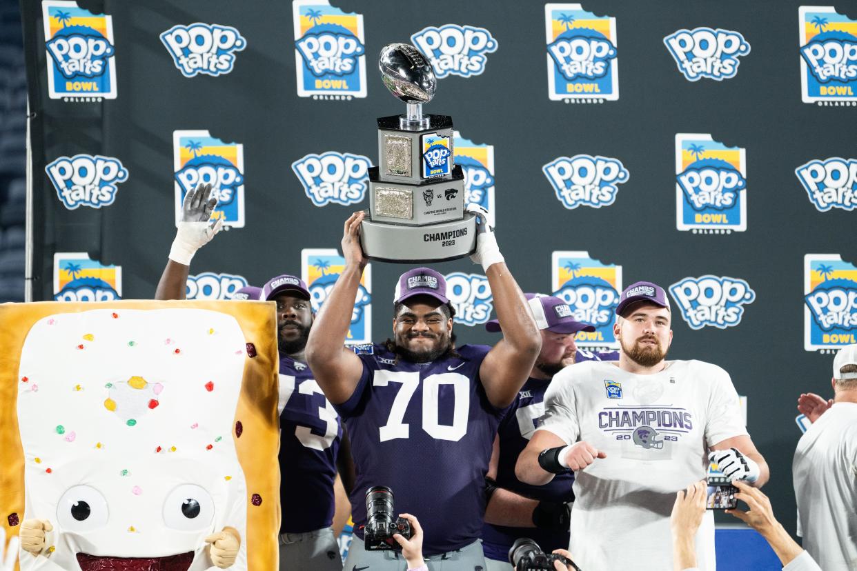 Kansas State offensive lineman KT Leveston (70) hoists the Pop-Tarts Bowl trophy as the Wildcats celebrate their 28-19 victory over North Carolina State at Camping World Stadium in Orlando, Fla.