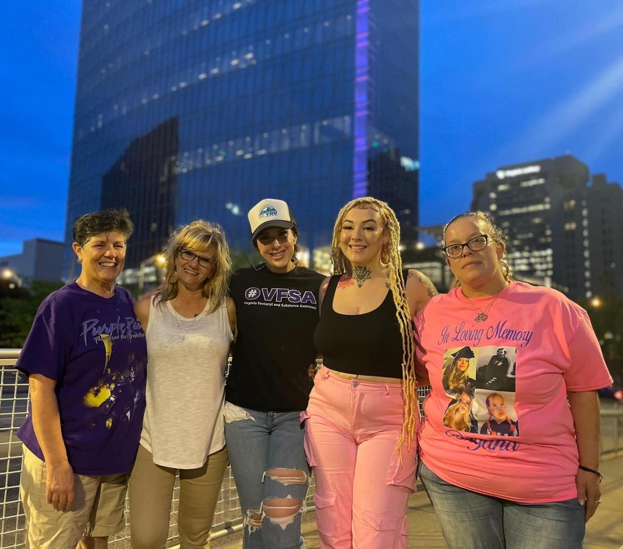 From left to right, Cheryl Clements, Belynda Gray, Karleen Wolanin, Virginia Fentanyl and Substance Awareness founder, Nicole Wolanin and Dorothy Winslow strike poses in front of the purple illuminated Dominion Energy building in Richmond on May 8, 2024.