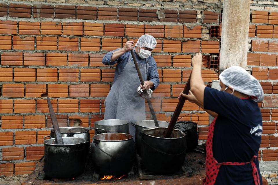 Walter Ferreira, left, and Laura Dure cook stew at a soup kitchen that feeds about 300 people daily in Luque, Paraguay, Monday, May 11, 2020. The U.N. World Food Program is warning that upward of at least 14 million people could go hungry in Latin America as the coronavirus pandemic rages on, shuttering people in their homes, drying up work and crippling the economy. (AP Photo/Jorge Saenz)