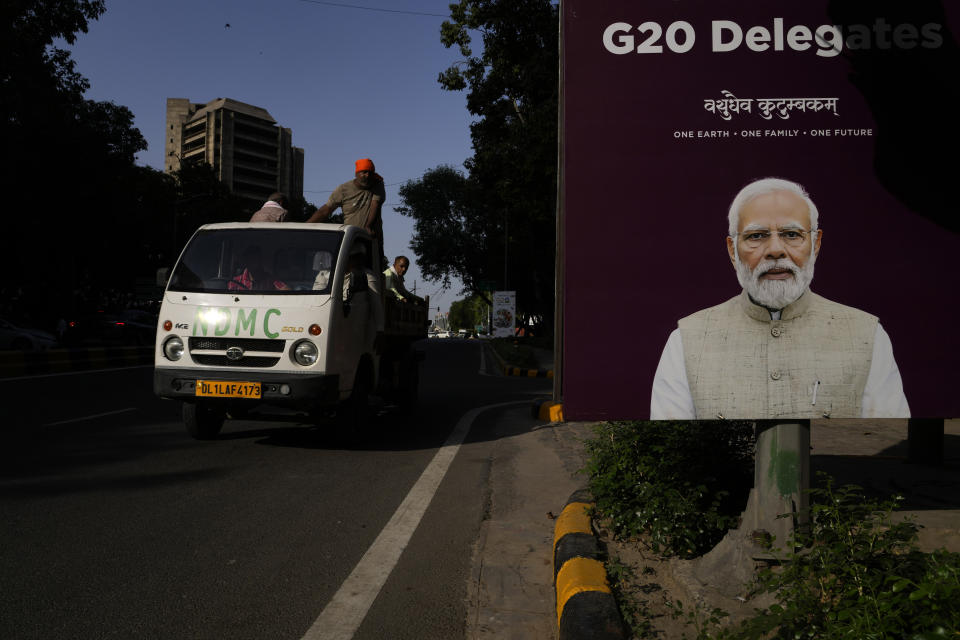 Civic workers engaged in cleaning the streets drive past a poster of Indian Prime Minister Narendra Modi welcoming delegates ahead of this week's summit of the Group of 20 nations in New Delhi, India, Monday, Sept. 4, 2023. The Indian government has seized upon its role as host of this year's G20 summit and mounted an advertising blitz that stresses India's growing clout under Prime Minister Narendra Modi. (AP Photo/Manish Swarup)