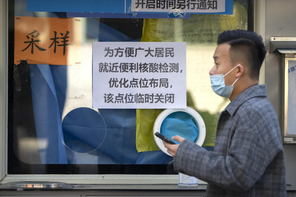 A man walks past a sign on a coronavirus testing site announcing that it is temporarily closed in Beijing, Tuesday, Nov. 15, 2022. The flagship newspaper of China's ruling Communist Party has called for strict adherence to the country's hardline "zero-COVID" policy, in an apparent attempt to guide public perceptions following a slight loosening of anti-virus regulations. (AP Photo/Mark Schiefelbein)