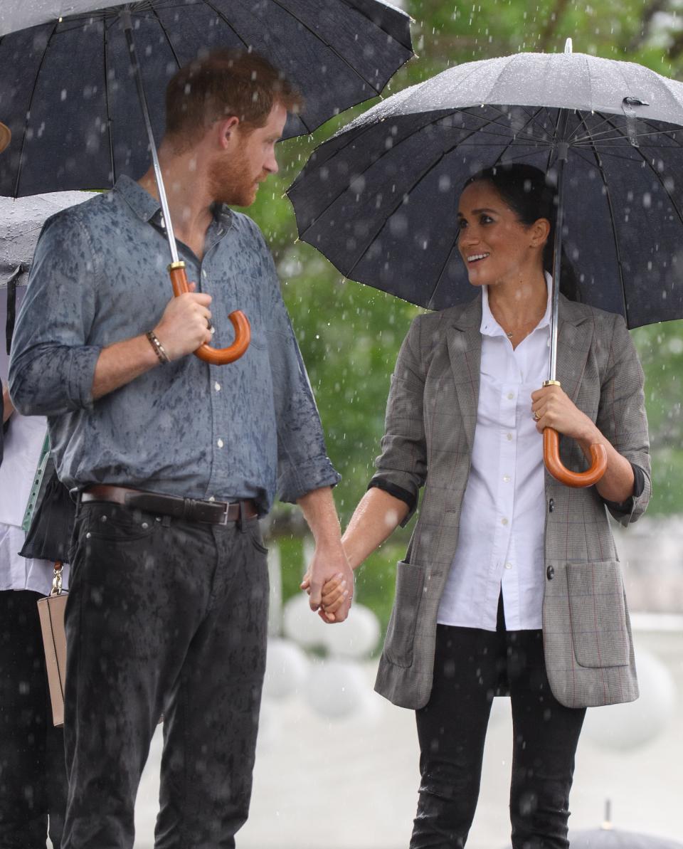 Pregnant Meghan Markle holds umbrella for Prince Harry during a speech about mental health on a recent official visit to Victoria Park in Dubbo, Australia.