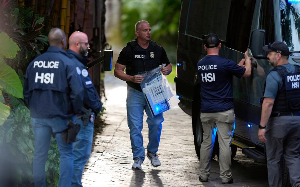 A law enforcement agent carries a bag of evidence to a van as federal agents stand at the entrance to a property belonging to rapper Sean "Diddy" Combs, Monday, March 25, 2024, on Star Island in Miami Beach, Fla