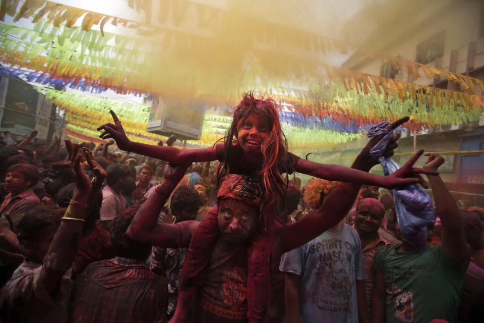 An Indian girl, face smeared with colored powder, sits on the shoulder of her father during celebrations marking Holi, the Hindu festival of colors, in Gauhati, India, Monday, March 17, 2014. The festival also marks the advent of spring. (AP Photo/Anupam Nath)