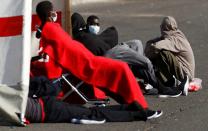 Migrants rescued in the Atlantic Ocean rest in a tent waiting to be transferred by the police, in the port of Arguineguin on the island of Gran Canaria