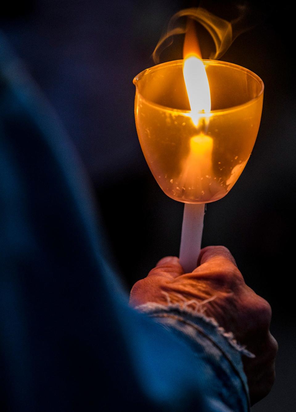 An attendee holds a candle on the Monroe County Courthouse lawn during the Homeless Memorial Vigil on Thursday, Sept. 29, 2022.